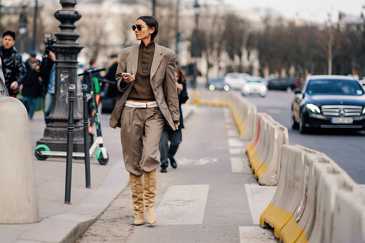Julia Pelipas wears sunglasses, a gray blazer jacket, a white belt, gray pants, beige boots, a polo shirt, outside Paco Rabanne, during Paris Fashion Week Womenswear Fall/Winter 2019/2020, on February 28, 2019 in Paris, France.