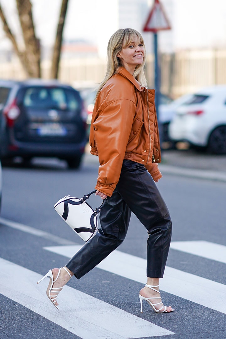 Jeanette Madsen wears a brown leather jacket, a Prada white and black bag, black leather pants, white shoes, outside MSGM, during Milan Fashion Week Fall/Winter 2020-2021 on February 22, 2020 in Milan, Italy.