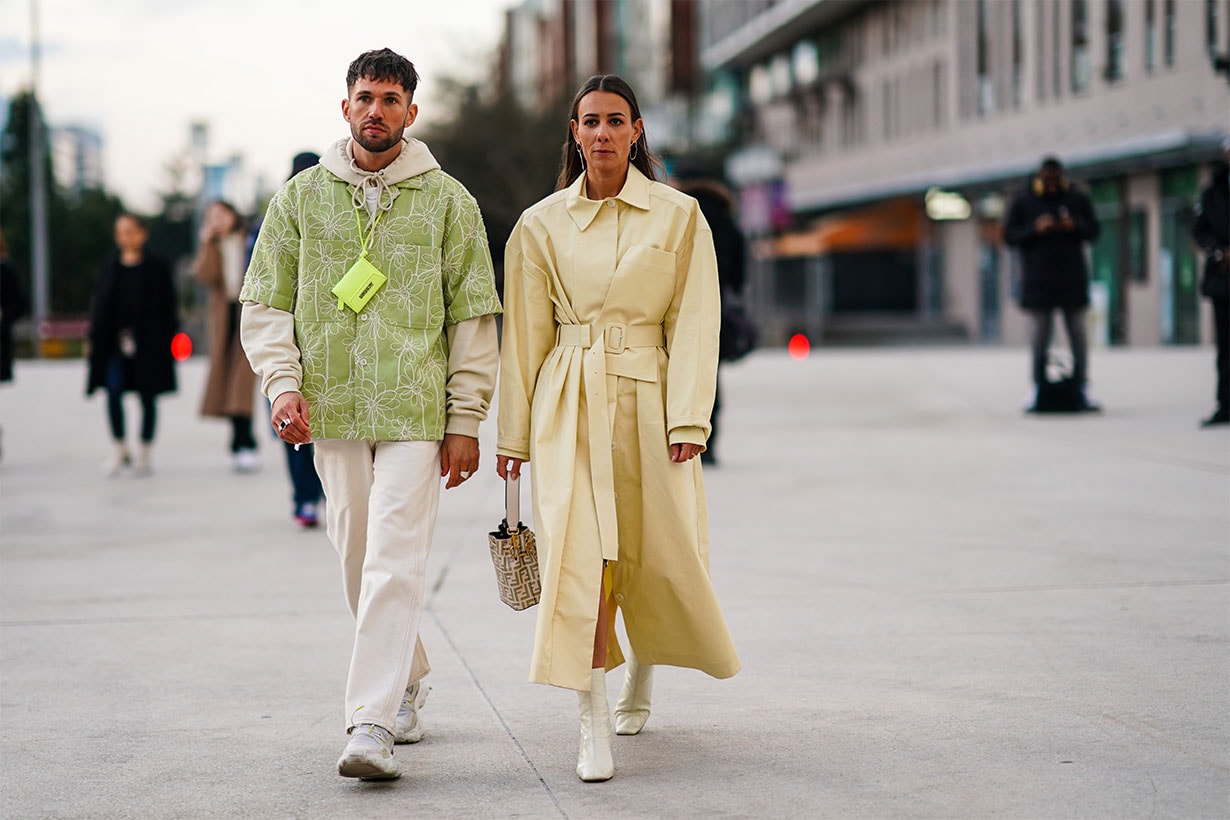 Jean-Sebastien Rocques (L) wears a beige hooded sweatshirt, rings, a pistachio-green short sleeves shirt with white floral embroideries, a neon-green Jacquemus bag, beige jeans, light grey and white sneakers ; Alice Barbier (R) wears earrings, a pale yellow trench coat, a Fendi bucket bag, shiny white square toe booties, outside Jacquemus, during Paris Fashion Week - Menswear F/W Fall/Winter 2020-2021 on January 18, 2020 in Paris, France.