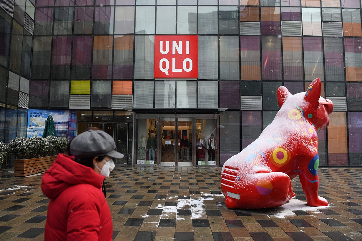 A woman wearing a face mask walks past a retail store at an empty shopping centre in Beijing