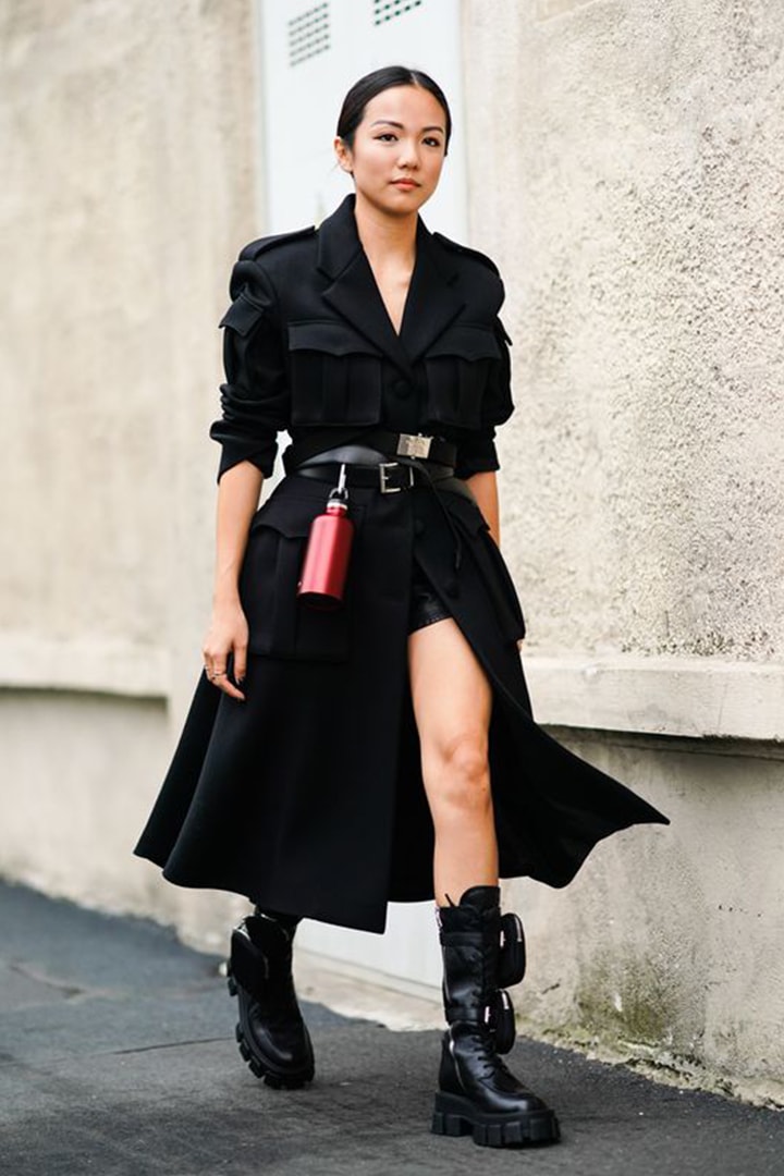Yoyo Cao wears a black long coat, a belt, a red attached water flask metallic bottle, outside the Prada show during Milan Fashion Week Spring/Summer 2020 on September 18, 2019 in Milan, Italy.