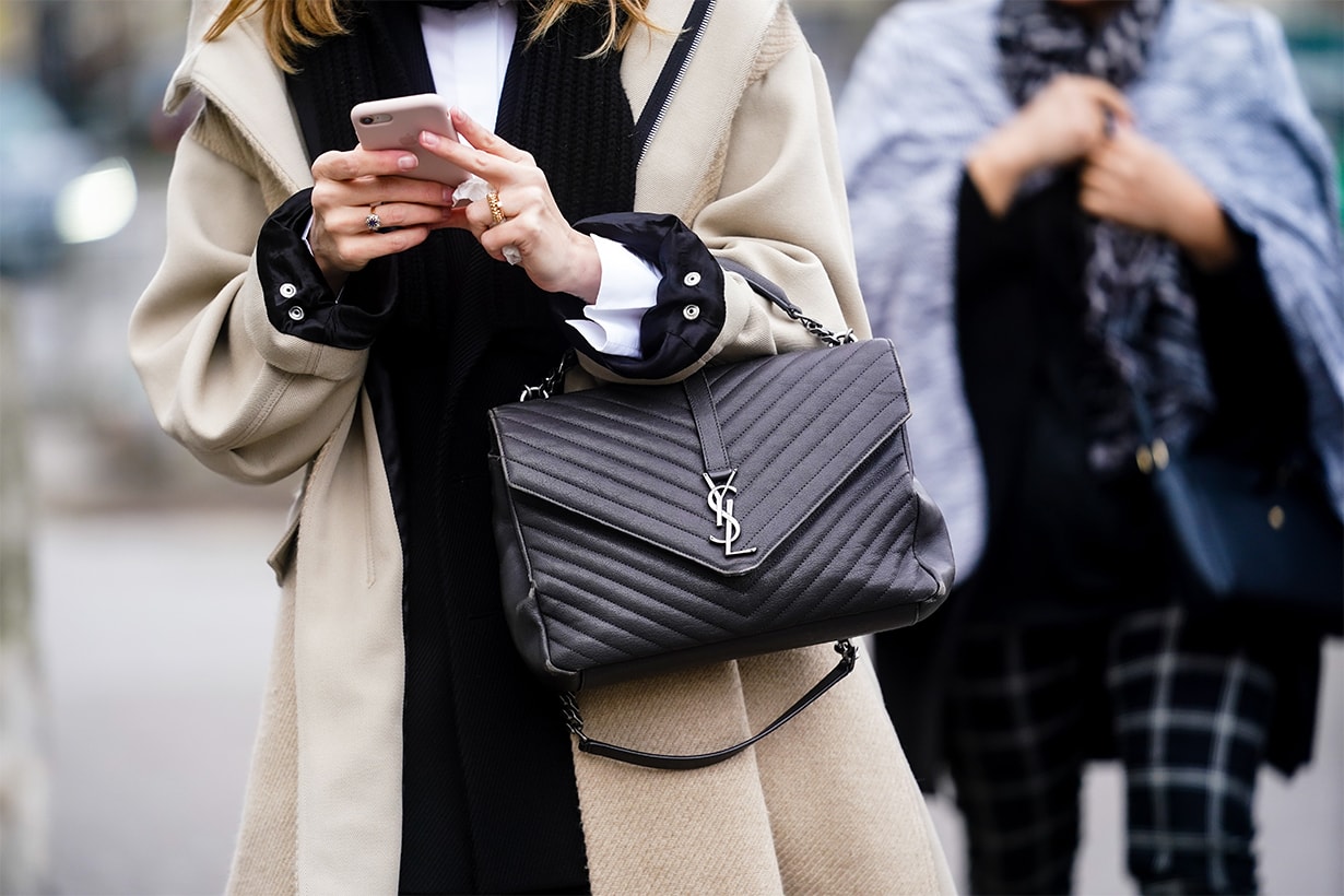 A guest wears a white wool coat, rings, a Saint Laurent YSL black leather quilted bag, outside Gauchere, during Paris Fashion Week - Womenswear Fall/Winter 2020/2021 on March 03, 2020 in Paris, France.