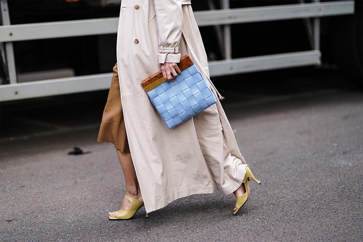 Linda Tol wears a gray trench coat, a brown leather skirt, shoes, a blue quilted bag, outside Max Mara, during Milan Fashion Week Fall/Winter 2020-2021 on February 20, 2020 in Milan, Italy.