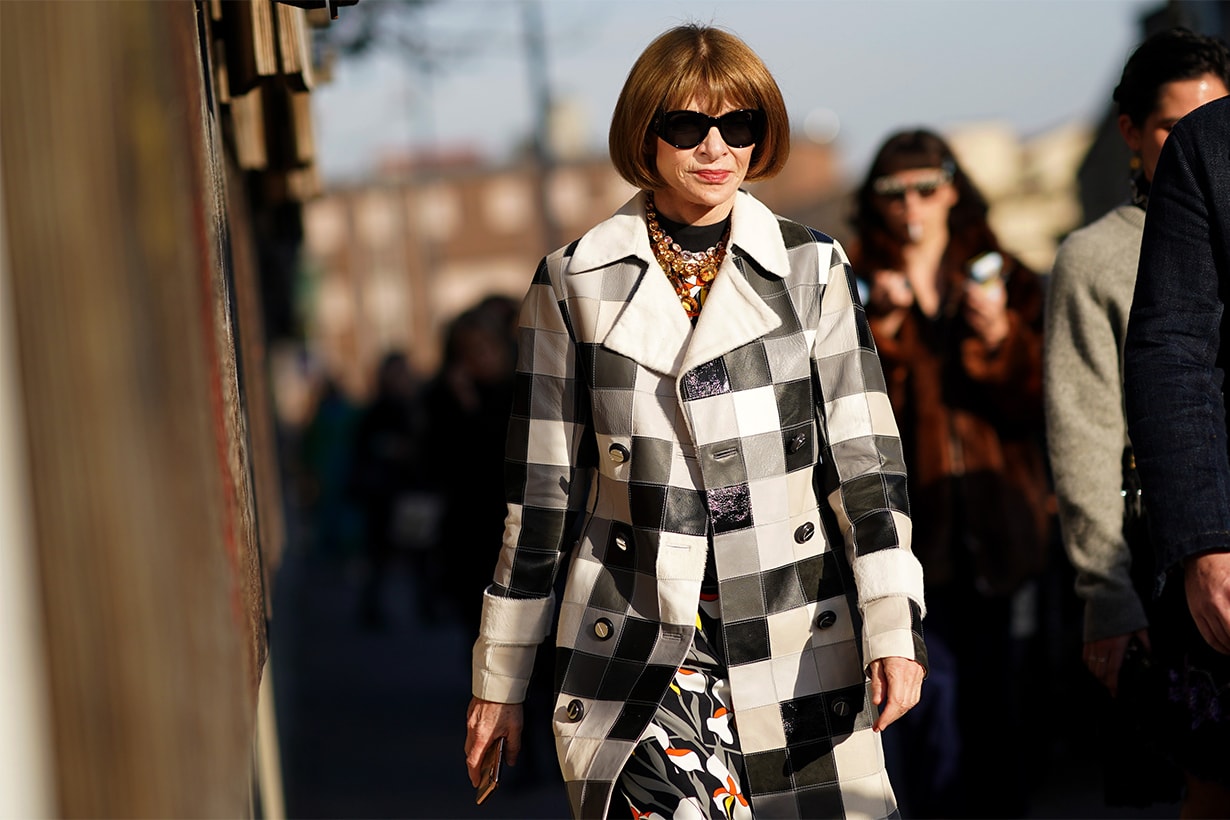 Anna Wintour wears sunglasses, a bejeweled necklace, a black and white checkered long trench coat, a floral print dress, outside Marni, during Milan Fashion Week Fall/Winter 2020-2021 on February 21, 2020 in Milan, Italy.