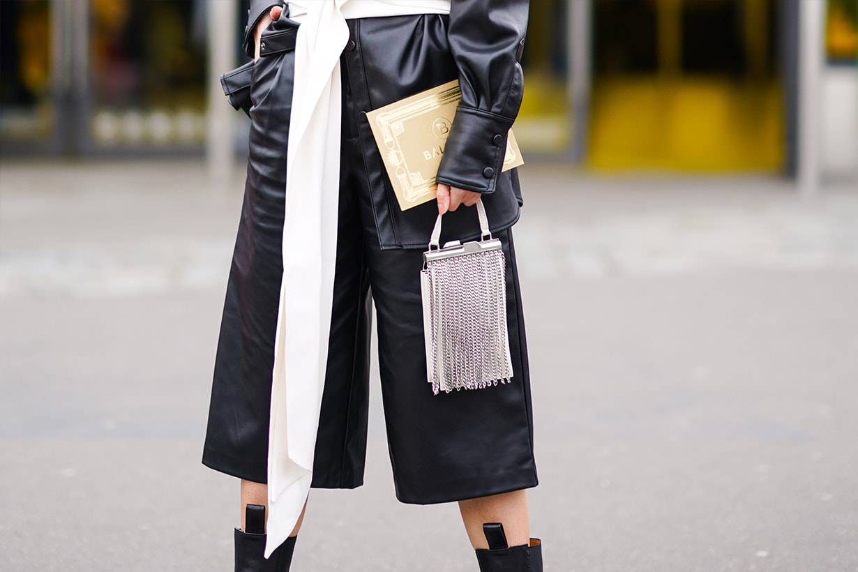 A guest a black leather shirt, black leather short pants, a white bag decorated with metallic fringes, outside Balmain, during Paris Fashion Week - Womenswear Fall/Winter 2020/2021, on February 28, 2020 in Paris, France. 