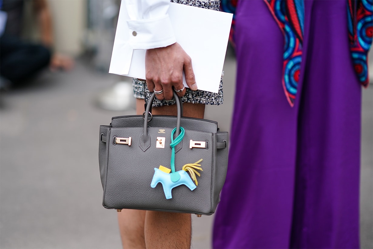 A guest wears a gray bag with an attachment depicting a blue horse, outside Hermes, during Paris Fashion Week - Menswear Spring/Summer 2020, on June 22, 2019 in Paris, France.