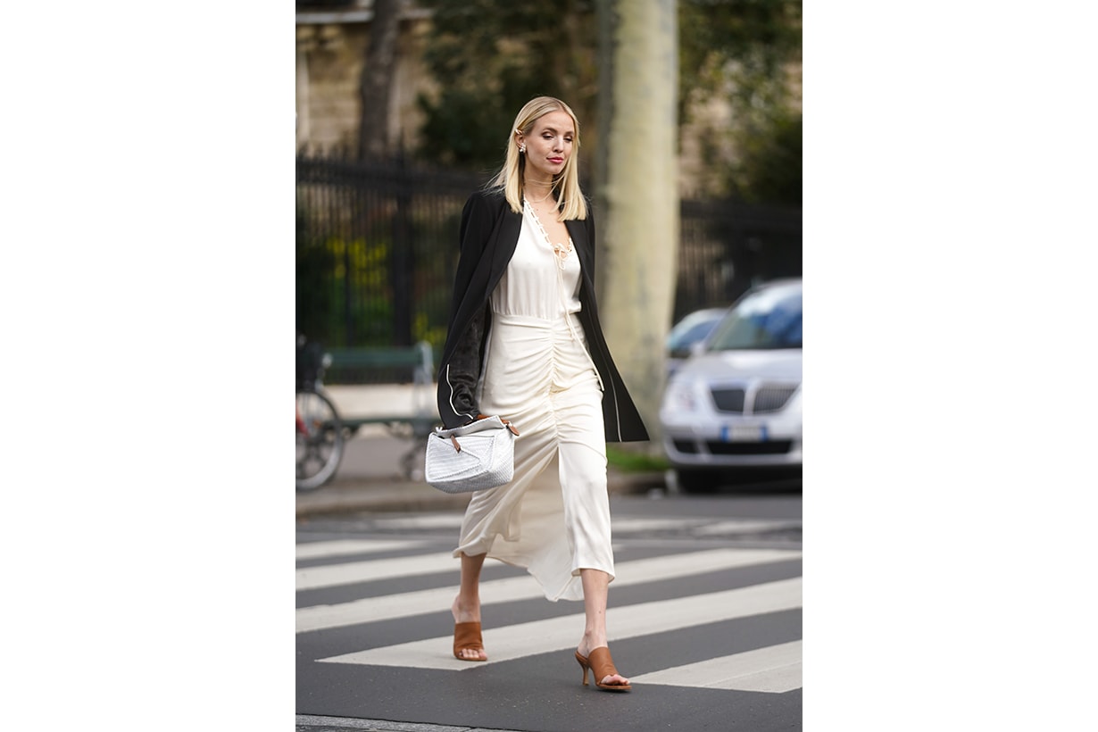 Leonie Hanne wears earrings, a black oversized jacket, a white dress, a white bag, brown pointy shoes, outside Gauchere, during Paris Fashion Week - Womenswear Fall/Winter 2020/2021 on March 03, 2020 in Paris, France. 