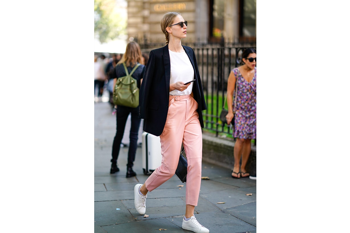 A guest wears a black blazer jacket, pink pants, white sneakers shoes, during London Fashion Week September 2018 on September 17, 2018 in London, England.