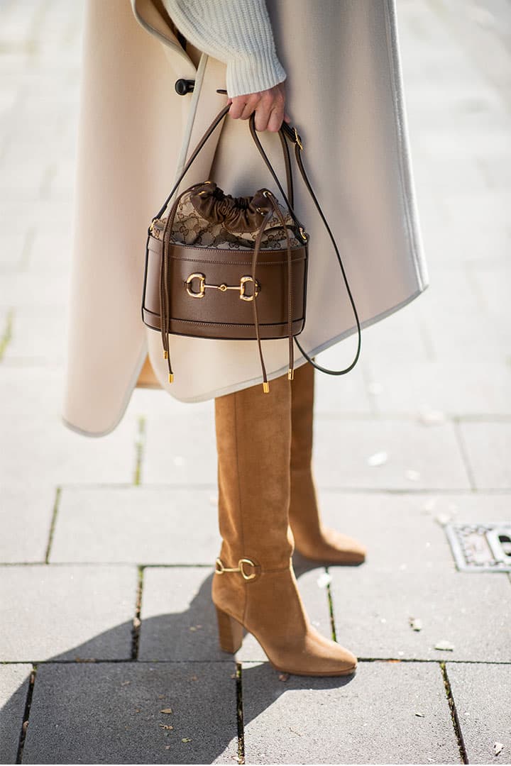 Alexandra Lapp is seen wearing Ariane Ernst hoop earrings in gold, Isabel Marant cape, Isabel Marant cap sleeve knitted jumper, Celine denim shorts, Gucci small 1955 Horsebit bucket bag in brown, Chloe Emma suede and leather knee boots in brown, all looks by Breuninger on September 18, 2020 in Berlin, Germany.