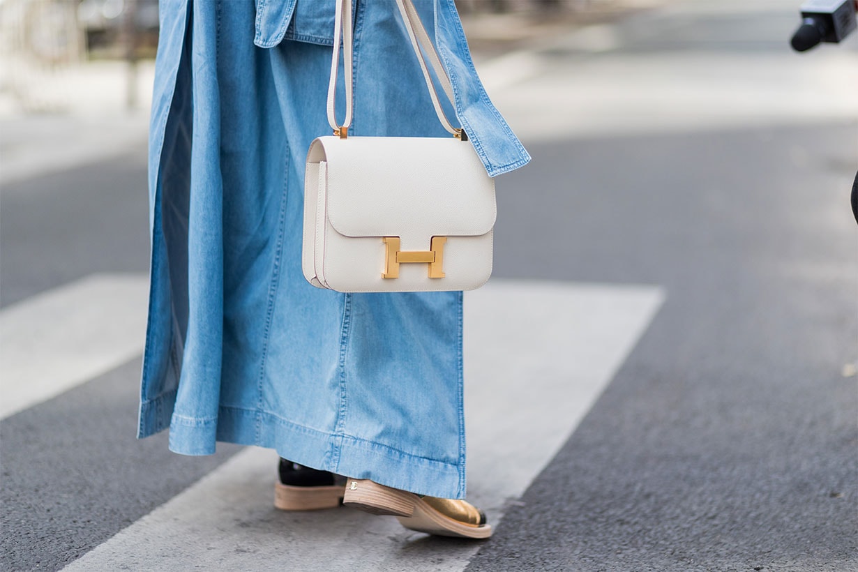 A guest wearing a blue denim coat, white pants, white Hermes bag outside Maison Margiela during Paris Fashion Week - Haute Couture Fall/Winter 2017-2018 : Day Four on July 5, 2017 in Paris, France.
