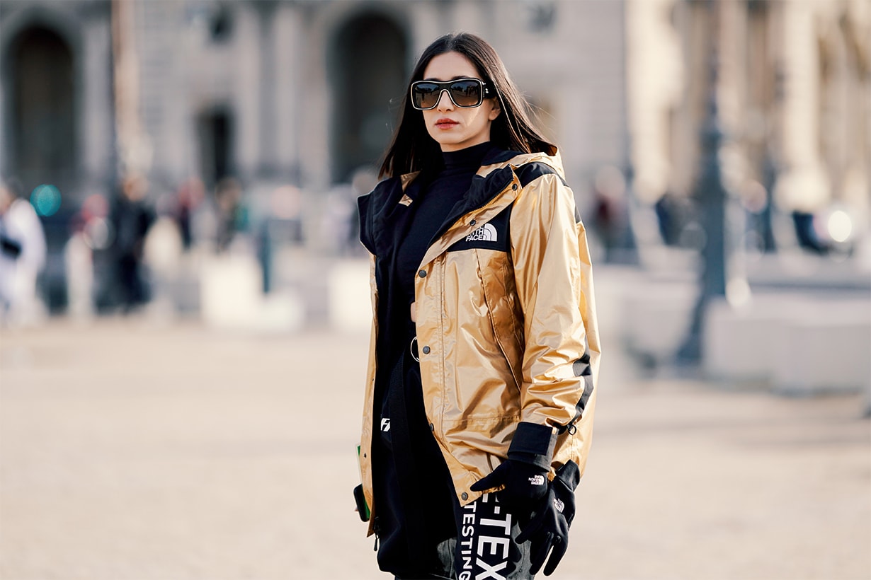 A guest wears a golden shiny bomber winter jacket from The North Face x Supreme, Off-White black pants, a cropped top, outside Off-White, during Paris Fashion Week Menswear F/W 2019-2020, on January 16, 2019 in Paris, France.